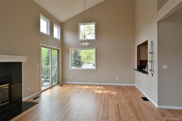 23846 Genesee Village Rd, Golden, CO 80401 - unfurnished living room with high vaulted ceiling, light wood-style flooring, a tile fireplace, and baseboards