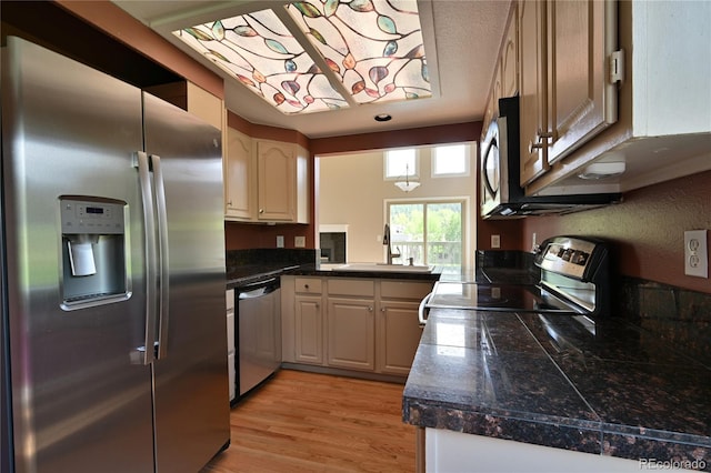 23846 Genesee Village Rd, Golden, CO 80401 - kitchen with appliances with stainless steel finishes, tile counters, a sink, and light wood-style flooring