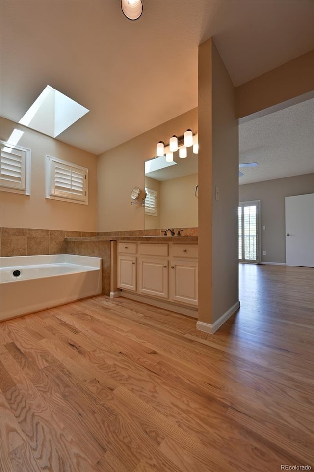 23846 Genesee Village Rd, Golden, CO 80401 - bathroom with a skylight, wood finished floors, vanity, and a garden tub