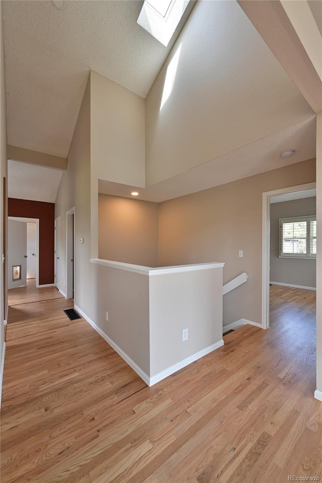 23846 Genesee Village Rd, Golden, CO 80401 - spare room featuring a skylight, light wood-type flooring, baseboards, and high vaulted ceiling