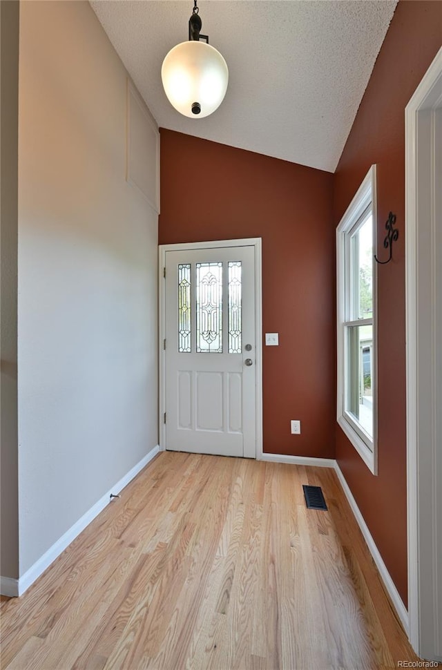 23846 Genesee Village Rd, Golden, CO 80401 - foyer entrance featuring lofted ceiling, light wood finished floors, baseboards, and a textured ceiling