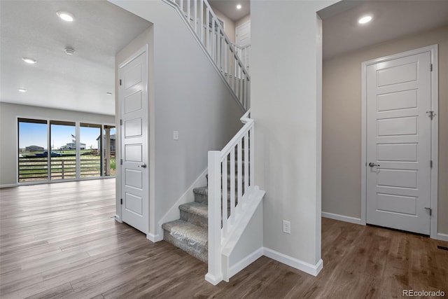 staircase with recessed lighting, wood finished floors, and baseboards