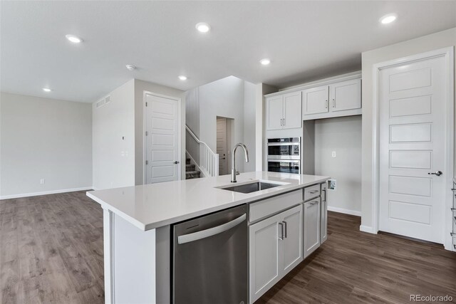 kitchen with white cabinets, dark hardwood / wood-style flooring, an island with sink, sink, and stainless steel appliances