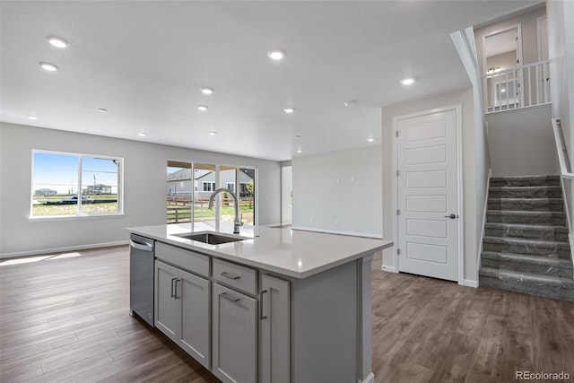 kitchen with a sink, wood finished floors, gray cabinets, and light countertops