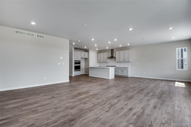 unfurnished living room featuring visible vents, recessed lighting, baseboards, and wood finished floors