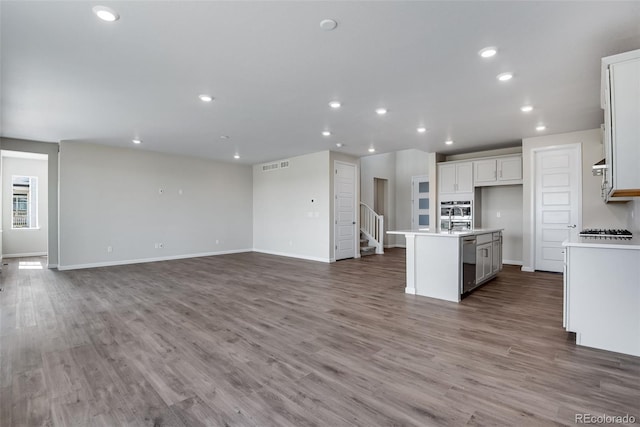 kitchen with visible vents, an island with sink, wood finished floors, open floor plan, and recessed lighting