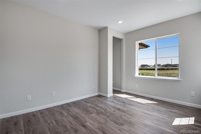 spare room featuring baseboards and wood finished floors