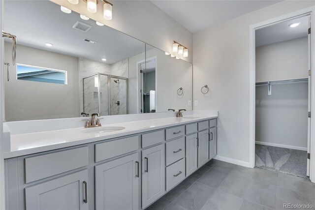 bathroom with a shower with door, vanity, and tile patterned flooring