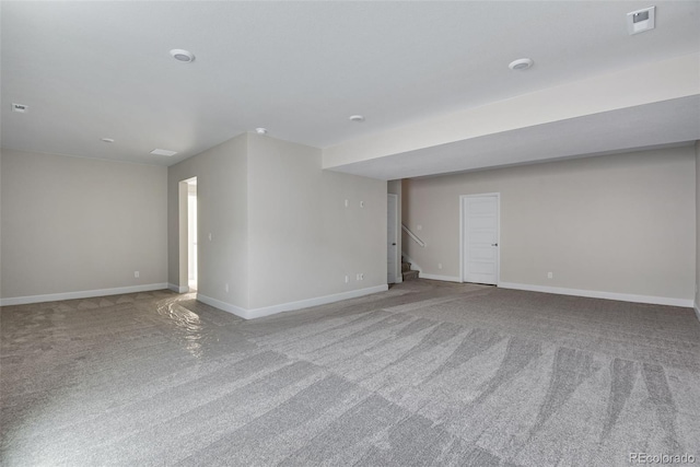 carpeted spare room with stairway, visible vents, and baseboards