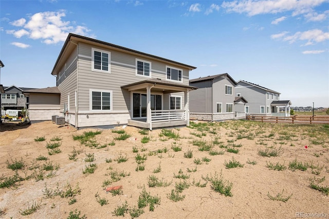 rear view of property with central AC unit and fence