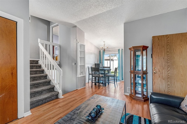 16980 E Stanford Ave, Aurora, CO 80015 - living area with a textured ceiling, a chandelier, stairs, wood finished floors, and vaulted ceiling