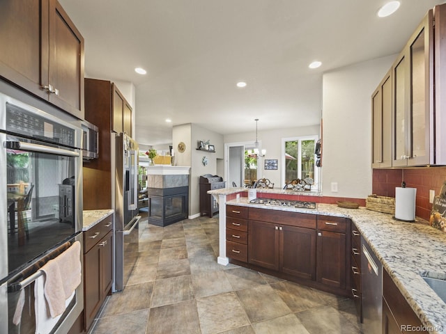 6432 S Robb Ct, Littleton, CO 80127 - kitchen with a peninsula, backsplash, a tile fireplace, stainless steel appliances, and recessed lighting