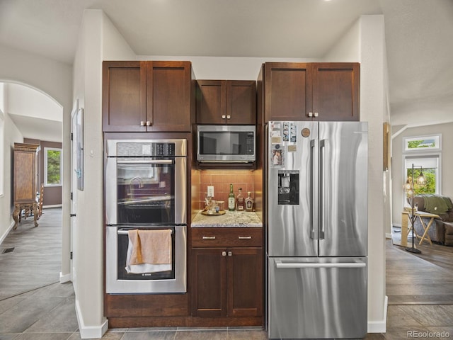 6432 S Robb Ct, Littleton, CO 80127 - kitchen with stainless steel appliances, baseboards, tasteful backsplash, light stone countertops, and arched walkways