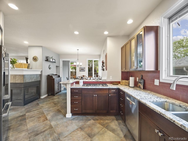6432 S Robb Ct, Littleton, CO 80127 - kitchen featuring appliances with stainless steel finishes, a peninsula, tasteful backsplash, a sink, and light stone counters