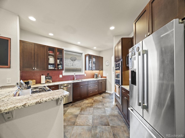 6432 S Robb Ct, Littleton, CO 80127 - kitchen with stainless steel appliances, backsplash, glass insert cabinets, a sink, and light stone counters