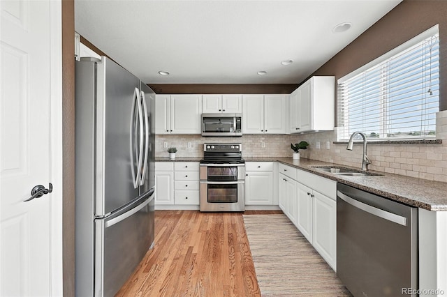 3543 Foxridge Trl, Highlands Ranch, CO 80126 - kitchen featuring appliances with stainless steel finishes, light wood finished floors, decorative backsplash, white cabinets, and stone countertops
