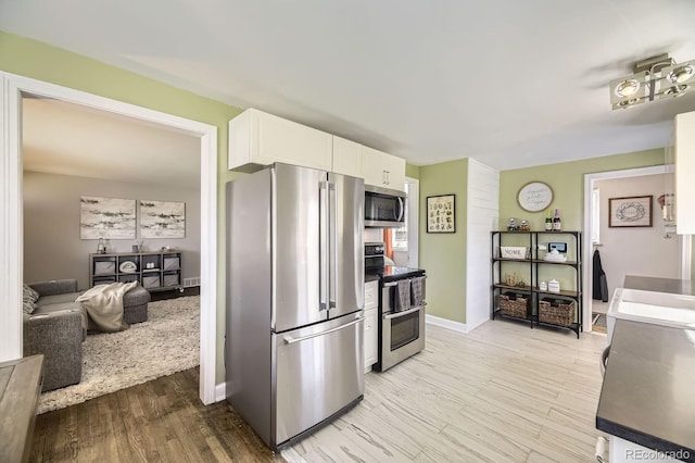 kitchen featuring white cabinets, light wood-style flooring, baseboards, and stainless steel appliances