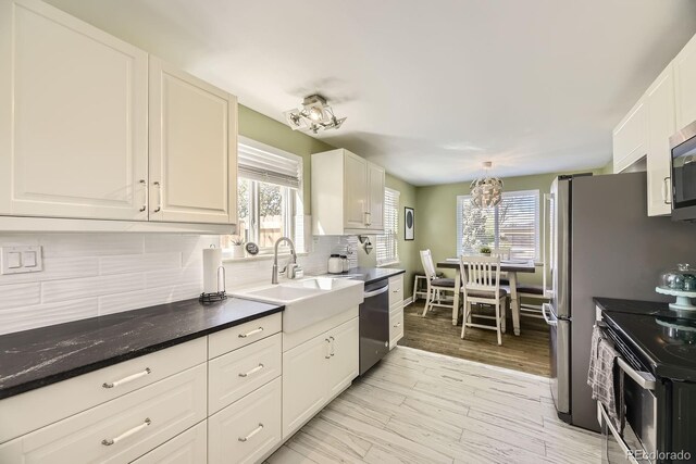 kitchen with a wealth of natural light, appliances with stainless steel finishes, white cabinetry, and a sink