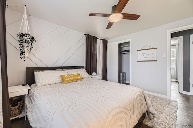 bedroom with baseboards, a ceiling fan, wood finished floors, and a closet