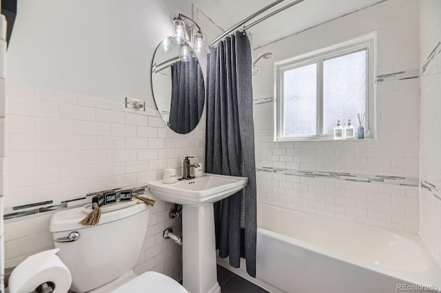 full bath featuring toilet, a sink, shower / bath combo with shower curtain, and tile walls