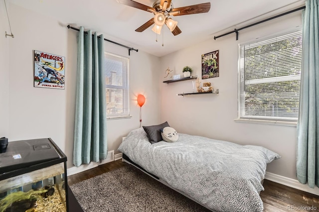 bedroom with baseboards, a ceiling fan, wood finished floors, and visible vents