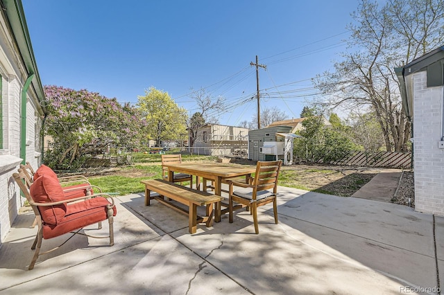 view of patio featuring an outdoor structure, a shed, a fenced backyard, and outdoor dining area