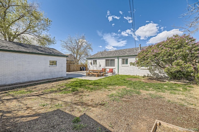back of property featuring fence, a lawn, and a patio