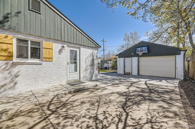 view of home's exterior featuring board and batten siding, a detached garage, brick siding, and driveway