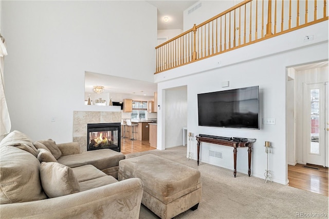 living area featuring visible vents, light colored carpet, a tile fireplace, and baseboards