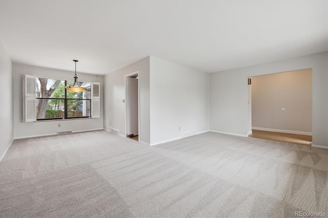 spare room with carpet flooring, visible vents, and baseboards