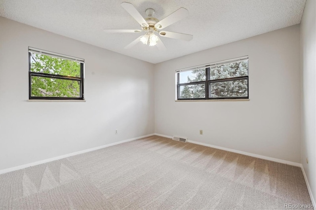 unfurnished room with light carpet, a textured ceiling, baseboards, and visible vents