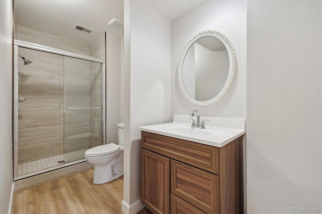 full bath with toilet, wood finished floors, visible vents, a shower stall, and vanity