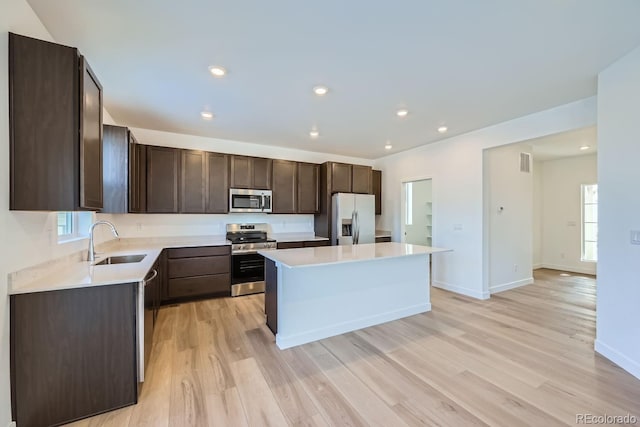 kitchen featuring a kitchen island, sink, light wood-type flooring, and appliances with stainless steel finishes