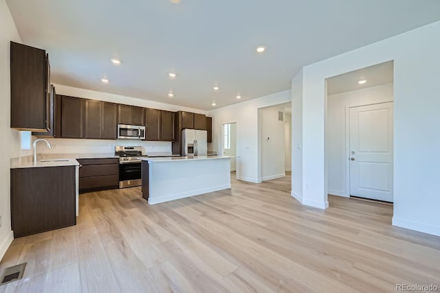 kitchen featuring sink, stainless steel appliances, a kitchen island, light hardwood / wood-style floors, and dark brown cabinetry