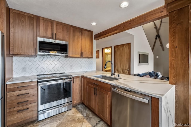 91200 Ryan Gulch Rd Unit 91222, Silverthorne, CO 80498 - kitchen featuring stainless steel appliances, a sink, backsplash, a peninsula, and brown cabinetry