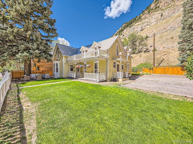 back of house with a balcony and a yard