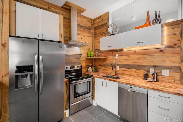 2530 Kensing Ct, Denver, CO 80211 - kitchen with appliances with stainless steel finishes, wood counters, wall chimney exhaust hood, dark tile patterned flooring, and white cabinets