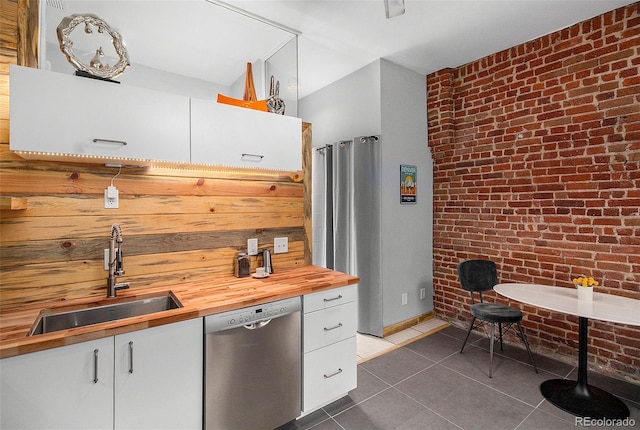2530 Kensing Ct, Denver, CO 80211 - kitchen featuring dishwasher, wood counters, brick wall, dark tile patterned flooring, and white cabinets