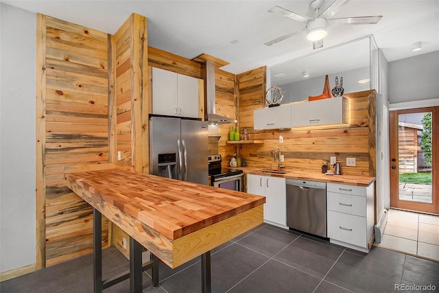 2530 Kensing Ct, Denver, CO 80211 - kitchen featuring stainless steel appliances, wooden counters, white cabinets, and wall chimney exhaust hood