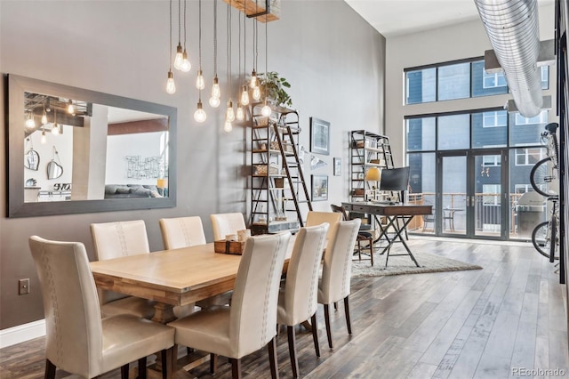 dining room with dark wood-type flooring, french doors, and a towering ceiling