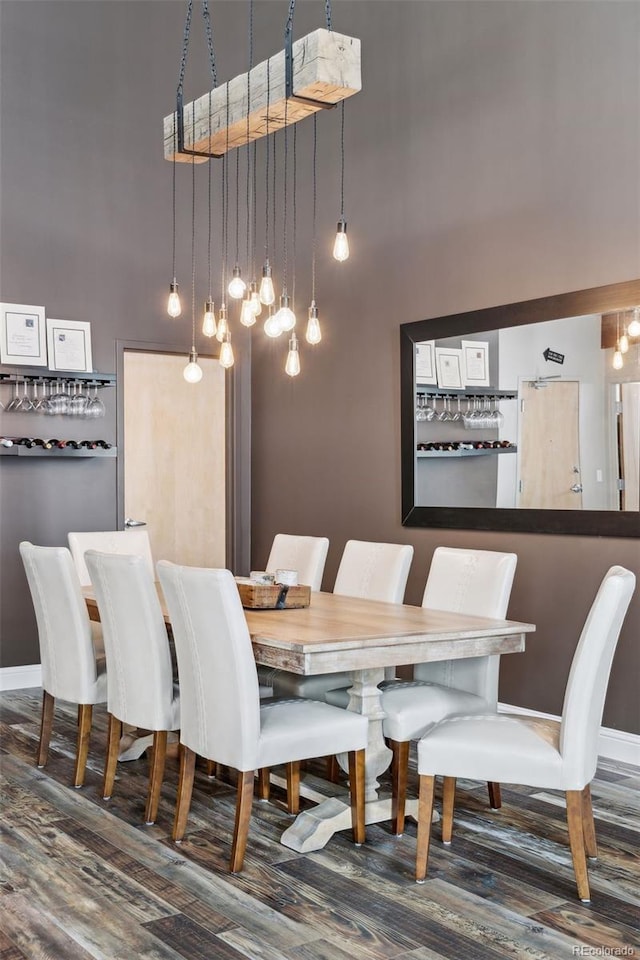 dining area with dark wood-type flooring and a towering ceiling