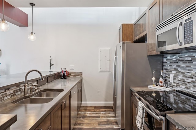 kitchen featuring sink, backsplash, stainless steel appliances, dark wood-type flooring, and hanging light fixtures