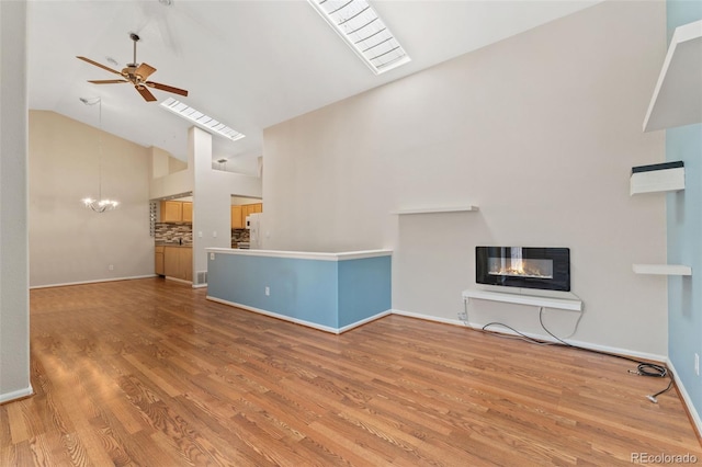 4195 W 111th Cir, Westminster, CO 80031 - unfurnished living room with high vaulted ceiling, a ceiling fan, wood finished floors, baseboards, and a chandelier