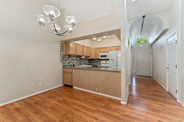 4195 W 111th Cir, Westminster, CO 80031 - kitchen with white appliances, a chandelier, light wood finished floors, a high ceiling, and tasteful backsplash