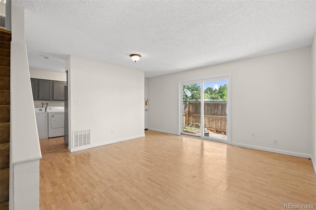 spare room featuring light hardwood / wood-style floors, a textured ceiling, and washing machine and dryer