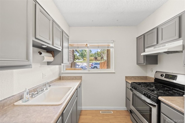 kitchen featuring appliances with stainless steel finishes, sink, light hardwood / wood-style floors, and a textured ceiling