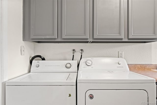 clothes washing area featuring cabinets and washer and dryer