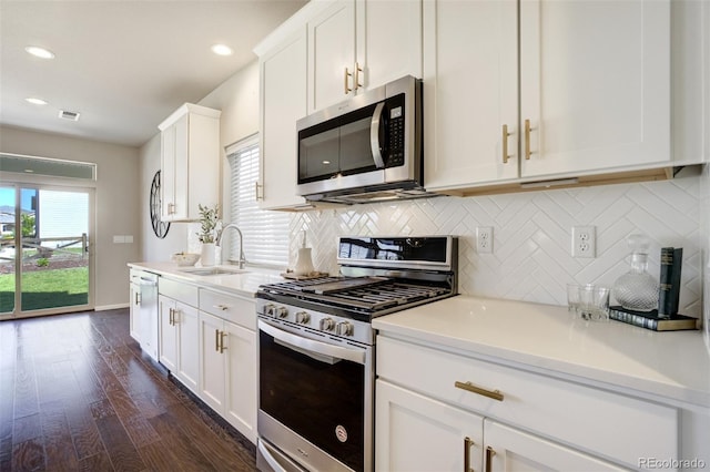 6689 Backcountry Loop, Colorado Springs, CO 80927 - kitchen with stainless steel appliances, tasteful backsplash, dark wood finished floors, white cabinets, and recessed lighting