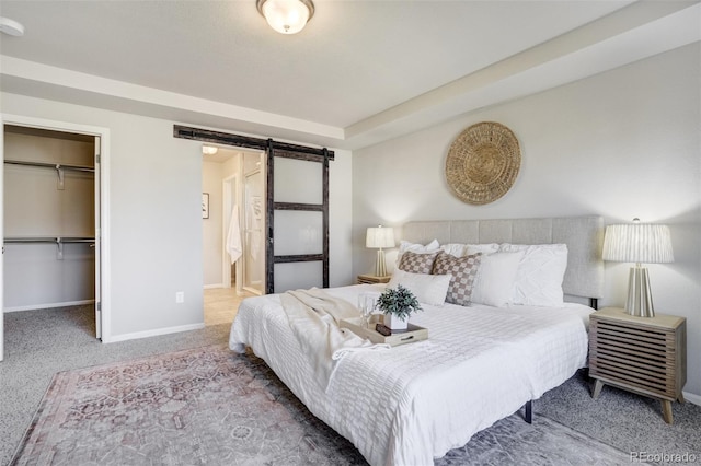 6689 Backcountry Loop, Colorado Springs, CO 80927 - carpeted bedroom featuring a barn door, a walk in closet, ensuite bathroom, and a closet