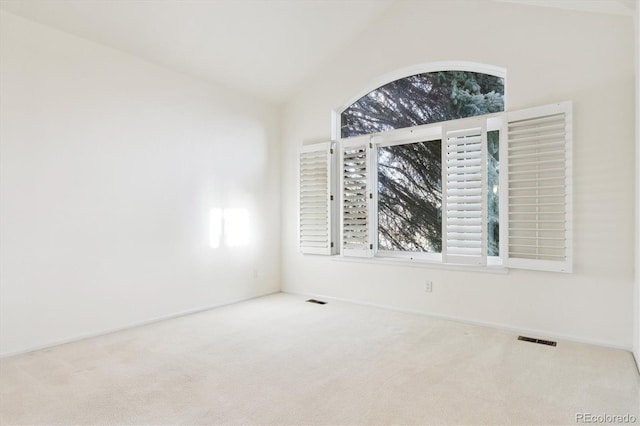 carpeted empty room featuring vaulted ceiling